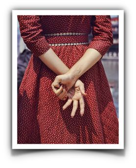 Fotoğrafın Adı Bilinmiyor Fotoğrafçı: Vivian Maier  Betimleyen: Serra ULUSOY  (Boğaziçi Üniversitesi, ED200 dersi öğrencisi)  Dikey dikdörtgen renkli fotoğrafta kırmızı üzerine beyaz puantiyeli elbise giymiş bir kadın sırtı dönük duruyor  Dirseklerinin biraz üstüne kadar görülüyor, üst gövdesi görülmüyor. Kollarını arkasında bilekleri üst üste gelecek şekilde birleştirmiş. Ellerinin tırnaklarında kırmız ojeler var. Yumruk yaptığı sağ eli ile avucu dışa doğru açık duran sol elinin işaret parmağını tutmuş.  Belinde iki tane paralel şeritli kemer var. Kemerde minik beyaz çiçekler sıra sıra dizilmiş. Elbisenin kol boyu kadının dirseklerinin biraz altında bitiyor. Elbisenin üstünde güneş ışığından kaynaklanan ellerinin oluşturduğu gölgeler görülüyor. Kadının arkasında birleştiği ellerinin beş santim aşağısına kadar elbise uzanıyor ve fotoğraf orda bitiyor.  Fonda belli belirsiz bir su birinkisi görülüyor, dış mekan olduğu görülmekte.