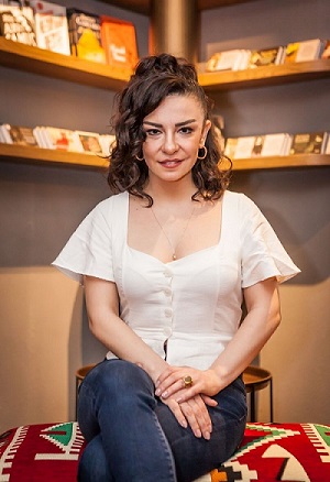 Müzisyen Fatma Turgut Dikey dikdörtgen biçimindeki renkli fotoğrafta Fatma Turgut 30 yaşlarında. Oturur şekilde poz vermiş olan sanatçının diz kapaklarından yukarısı fotoğraf içine alınmış. Gömlek ve pantolon giyen müzisyen gülümseyerek doğrudan kadraja bakıyor. Bulanık olan arka planda ikisi sağda ikisi solda olmak üzere dört adet raf bulunuyor. Sol üstteki rafta kitaplar, diğer raflarda ise albümler var. Müzisyen otantik olarak adlandırabileceğimiz geometrik şekillerden ve koyu renklerden oluşan kilim kaplamalı geniş bir tabure üstünde oturuyor.  Beyaz ve pürüzsüz tenli Fatma Turgut’un saçları siyah, dalgalı ve omuzlarına kadar iniyor. Saçlarının bir kısmı arkadan bağlanmış ve yüzünün sağ tarafından bir tutam kakül gibi aşağı bırakılmış. Uzun ve ince surat hatlarına sahip, çenesi hafif sivri. Sol gözü sağ gözünden biraz daha büyük ve kahve rengi gözleri hafif çekik. İnce ve sert hatlı siyah kaşları var. Üst dudağı alt dudağından daha ince olan kadın üst dişleri gözükecek şekilde gülüyor. Kulakları büyük ve ayrık. Alnı geniş ve dikdörtgen şeklinde. Gülümsemenin etkisi ile dudak kenarlarından burnuna doğru iki çizgi uzanıyor. Burnu ince, ucu sivri ve kemikleri belli. Gözlerinin altındaki torbalar ikinci bir çizgi oluşturmuş. Gömleğinin açık yakası kalın ve kısa boynunu açıkta bırakmış.  Müzisyenin iki kulağında da altın sarısı renginde halka küpeler mevcut. Kadın üstünde omuz kısmındaki kumaşları geniş olan beyaz renkli düğmeleri olan bir gömlek var. Yakası göğüs çatalının hizasına kadar açık. Boynundaki ucunda beyaz yuvarlak inci olan kolye göğüs çatalına kadar iniyor. Kot pantolon giymiş olan sanatçı sağ dizini sol dizinin üstüne almış ve ellerini bacaklarının üstüne koymuş. Sol eli sağ elinin üstünde. Sol elinin yüzük parmağına koyu sarı renkli büyük bir yüzük takmış.