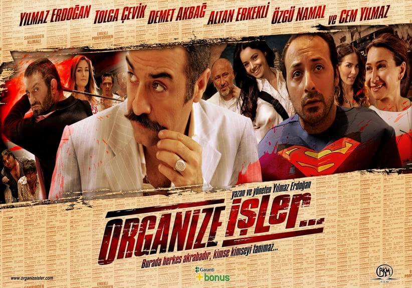 Organize İşler Betimleyen: Hatice ÇULHA  Arka plan rengi olarak yavruağzının hâkim olduğu yatay formdaki afişin üste yakın orta kısmında hafif sola doğru eğik ve 5-6 cm kalınlığındaki şerit içerisinde filmden 12 karakter yer almakta. En önde üzerinde kan lekeleri olan beyaz ceketiyle ve içine giydiği yakası açık beyaz gömleğiyle Asim Noyan (Yılmaz Erdoğan) var. Asim Noyan sol tarafa doğru kaşlarını kaldırmış bir şekilde bakıyor ve yüzük parmağında gümüş rengi ve biraz büyük yuvarlak bir yüzük olan sol eliyle de kaytan tarzı bıyığının ucunu tutuyor. Asim Noyan’ın hemen omzunun arkasında ve sağ tarafta ise üzerinde Süpermen kıyafeti olan ve alnındaki çizgiler ve parlayan gözleriyle üzgün gibi duran Süpermen Samet (Tolga Çevik) yer alıyor. Süpermen Samet sağ üst kısma doğru ağzı hafif açık bir şekilde bakıyor. Diğer karakterler ise arkalarında yer alıyor.  Afişin sol kısmında yer alan karakterlerden dördü oldukça arka tarafta ve dayak yemiş gibi kanlar içerisinde. En solda ve alt kısımda olanlardan soldaki biraz kilolu, beyaz çizgili lacivert gömleğinin yakası oldukça açık olan Üzeyir (Erdal Tosun), hemen yanında yakası açık beyaz gömleğiyle ve yanağı şişmiş bir halde Tugay Selimoğlu (Tuncer Salman) yer alıyor.  Onların oldukça önünde ve hemen sağlarında vücudu sola dönük, elinde demir bir çubuk olan ve üzerinde siyah gömleğiyle sol kaşını kaldırmış Müslüm Duralmaz (Cem Yılmaz) yer alıyor. Müslüm Duralmaz’ın hemen sağ yanında ve arkasında sağa doğru bakan bakır saçlı hafif gülümseyen bir kadın, Suna (Hande Dane) var. Kadının sağ tarafında ve oldukça arka kısımda yüzü kanlı bir şekilde bakan Silvio (Öner Erkan) sağında belli belirsiz görünen Ersin (Ersin Korkut) bulunuyor. Asim Noyan ve Süpermen Samet’in arasında ve arka kısımda ise sağa doğru bakan ve sol eli boynunda olan Yusuf Ziya Ocak (Altan Erkekli) ile uzun siyah saçları olan ve gülümseyen Umut Ocak (Özgü Namal) yer alıyor. Süpermen Samet’in hemen sağında ve arkada saçları maşalı, yüzü sağa dönük ve gülümseyen Nilüfer (Ebru Akel) ile afişin en sağında ise yüzü sola dönük, saçları toplu olan ve gülümseyen Nuran Ocak (Demet Akbağ) var. Karakterlerin yer aldığı bu şeritin üst kısmında ise 1 cm boyunda kırmızı ve siyah yazı rengi ile büyük harflerle yazılmış karakterlerin adları soldan sağa şu şekilde: YILMAZ ERDOĞAN, TOLGA ÇEVİK, DEMET AKBAĞ, ALTAN ERKEKLİ, ÖZGÜ NAMAL VE CEM YILMAZ.  Şeritin alt ve orta kısmında ise filmin adı yer alıyor. Filmin adı da, karakterlerin adı ve şerit gibi sola eğik. Organize kelimesi büyük harflerle yazılırken işler kelimesi küçük harflerle yazılmış. Kırmızı ve siyah renklerle yazılmış ve 2-3 santimetre arasında olan filmin ilk kısmının üstünde organize kelimesi boyunca tine aynı renkte bir çizgi yer alırken aynı tarz çizgi ikinci kelime olan ve devamında üç nokta olan işler kelimesinin altında yer alıyor. İşler kelimesinin üst kısmında küçük harflerle “yazan ve yöneten Yılmaz Erdoğan” yazıyor. Filmin adının orta kısmında ve hemen altında ise aynı renklerle yarım santimetre boyunda “Burada herkes akrabadır, kimse kimseyi tanımaz…” yazısı yer alıyor. Yazının hemen altında Garanti ve Bonus amblemleri bulunuyor. Afişin sol alt köşesinde siyah renkte “www.organizeisler.com” yazarken sağ alt köşesinde ise BKM filmin amblemi yer alıyor.
