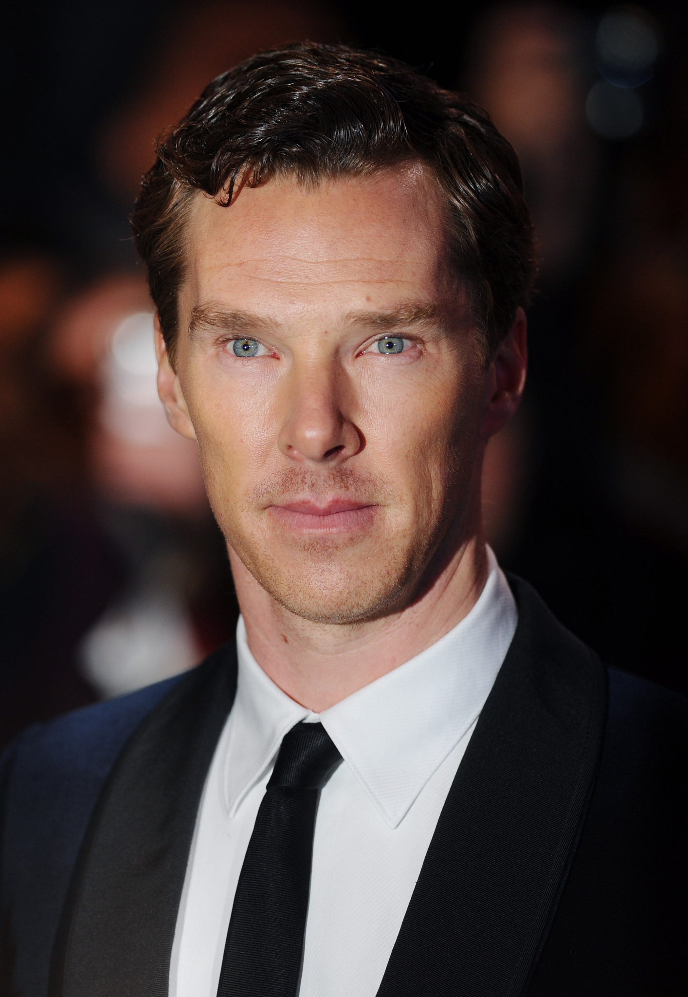 Oyuncu Benedıct Cumberbatch Betimleyen: Gökçe ALTINÇEKİÇ (Boğaziçi Üniversitesi, ED200 dersi öğrencisi) Dikey dikdörtgen şeklinde ve renkli olan fotoğraf karesinde Benedict Cumberbatch’in sadece göğsünden yukarı kısmı görünüyor. Cumberbatch’in bedeni çok hafif sağına dönükken yüzü direkt kameraya bakıyor. Ayrıca yüzünün sol tarafına bir gölge düştüğünden dolayı bu kısım karanlık görünüyor. Cumberbatch, fotoğrafta otuzlu yaşlarının sonlarında. Uzun ve düz bir yüz şekline sahip olan Cumberbatch’in çekik ve çok büyük olmayan mavi gözleri var. Kahverengi, gür ve hafif kavisli olan kaşları gözlerine çok yakın duruyor. Sol kaşının biraz üstünde ve sağ kenarına doğru ve iki kaşının ortasında sol kaşına daha yakın, diğerine göre daha küçük iki tane kahverengi beni bulunuyor. Geniş olan alnının orta kısmında, üsttekinin tüm alnını kapsayan, alttakinin de sağ tarafta biten iki tane yatay alın çizgisi bulunuyor. Uzun ince burun duvarına sahip olan Cumberbatch’in, hafif geniş burun kanatları ve sivri olmayan dik bir burun ucu var. Cumberbatch’in elmacık kemikleri belirgin bu yüzden yanaklarının elmacık kemiklerinin aşağısında kalan kısmı hafif içe doğru çökük görünüyor. Fotoğrafta gülmeyen Cumberbatch’in pembe olan üst dudağı ince ve v şeklinde keskin bir hatta sahip. Alt dudağı ise pembe, düz ve üst dudağına göre daha kalın. Bıyık bölgesinde, çenesinde, boynunun gözüken tarafının yarısında ve yanaklarının bıyık bölgesi hizasında seyrek, kısa ve kahverengi sakalları bulunuyor. Büyük ve kafasına yapışık duran kulaklarından sol taraftaki karanlıkta kaldığından dolayı çok fazla görünmüyor.  Geniş ve sivri olmayan bir çeneye sahip olan Cumberbatch’in çenesinden yanaklarına doğru çizgiler oluşmuş. Siyah ve kısa saçlarının ön kısmı yanlarından biraz daha gür, uçları dalgalı ve sağa doğru ayrılmış durumda. Saçlarının üst kısımlarının bazı yerleri ışıktan dolayı parlamış ve beyaz görünüyor. Yüzünden Cumberbatch’in zayıf olduğu anlaşılıyor. Uzun ve ince olan boynunun orta kısmının sağ tarafında açık kahverengi bir ben bulunuyor ayrıca adem elması da belirgin. Cumberbatch’ın boynunun alt tarafını yakası sivri uçlu olan düz, beyaz bir gömlek kaplıyor. Yakasında küçük bir düğümle bağlanmış siyah ince bir kravat takıyor. Beyaz gömleğinin üstüne siyah bir ceket giyiyor ve önünün büyük bir kısmını örtmüş duruma.  Geniş olan omuzlarının bir kısmı kadraja sığmamış.   Fotoğraf karesinin arka tarafı tamamen siyah, beyaz ve kahverengi flu renklerden oluşuyor.
