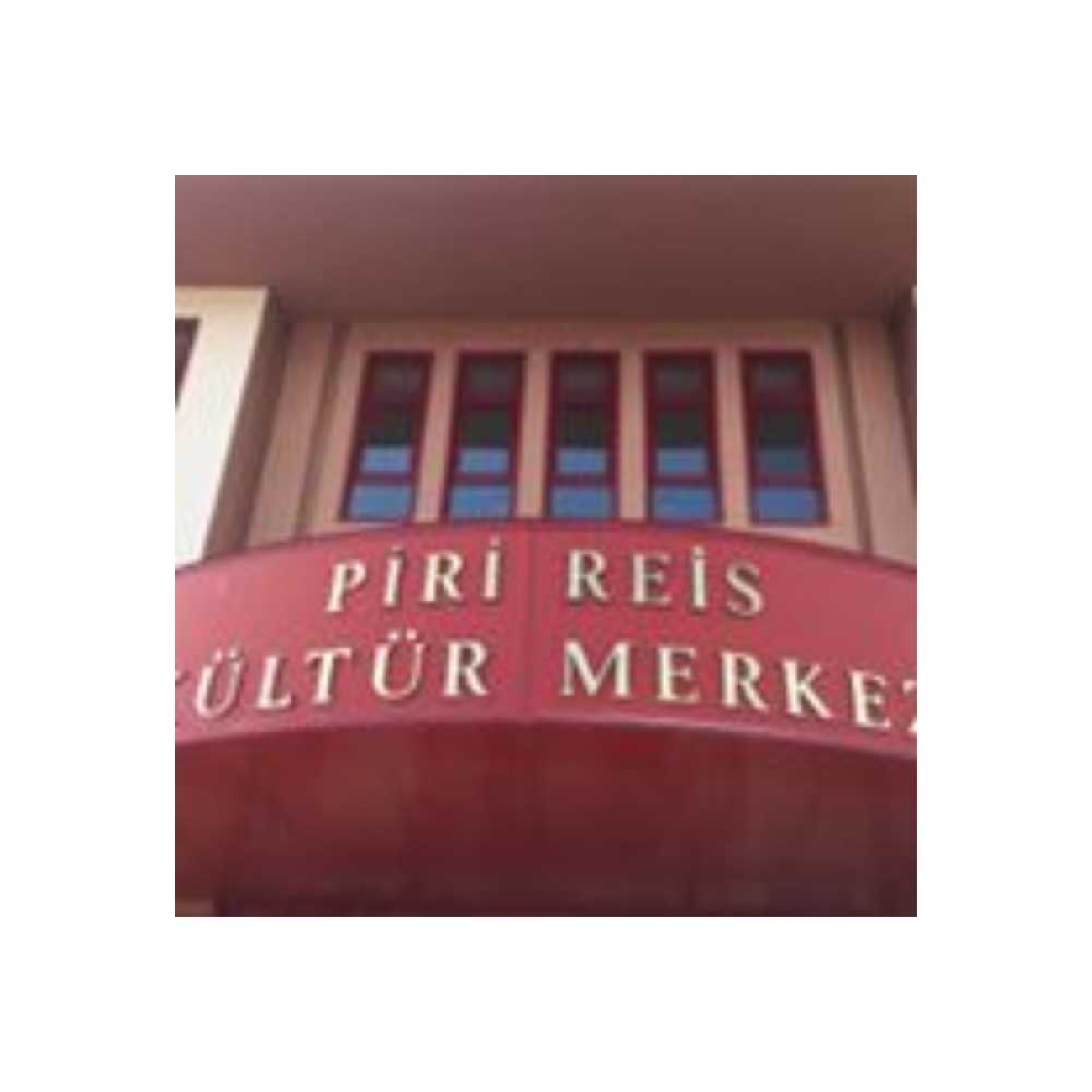 Piri Reis Kültür Merkezi'nin girişini gösteren bir fotoğraf. Kırmızı zeminli dışbükey tabela üzerinde merkezin adı yazılı; arka planda ise bina cephesindeki pencereler yer alıyor.
