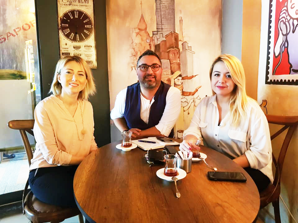 SEBEDER Nisan Medya  ile Buluştu Cafe Pier'de çekilen fotoğrafta Emine Kolivar ve Nisan Medya'dan sarışın bir kadın ve kısa saçlı bir erkek objektife gülümsüyor.